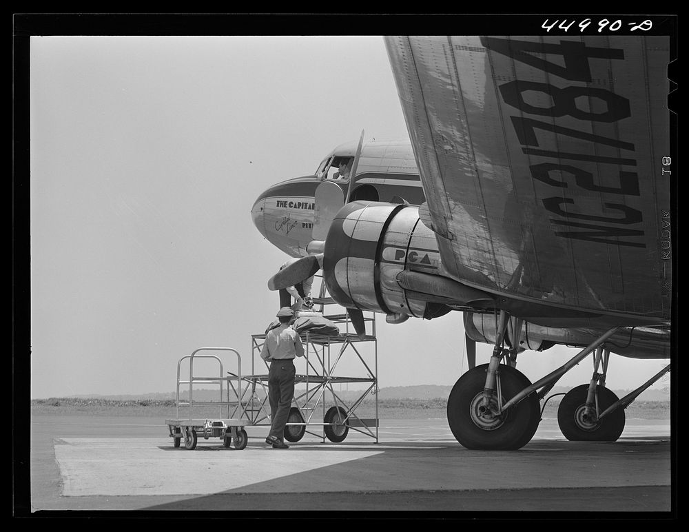 Loading baggage aboard an airliner. Washington D.C. municipal airport. Sourced from the Library of Congress.