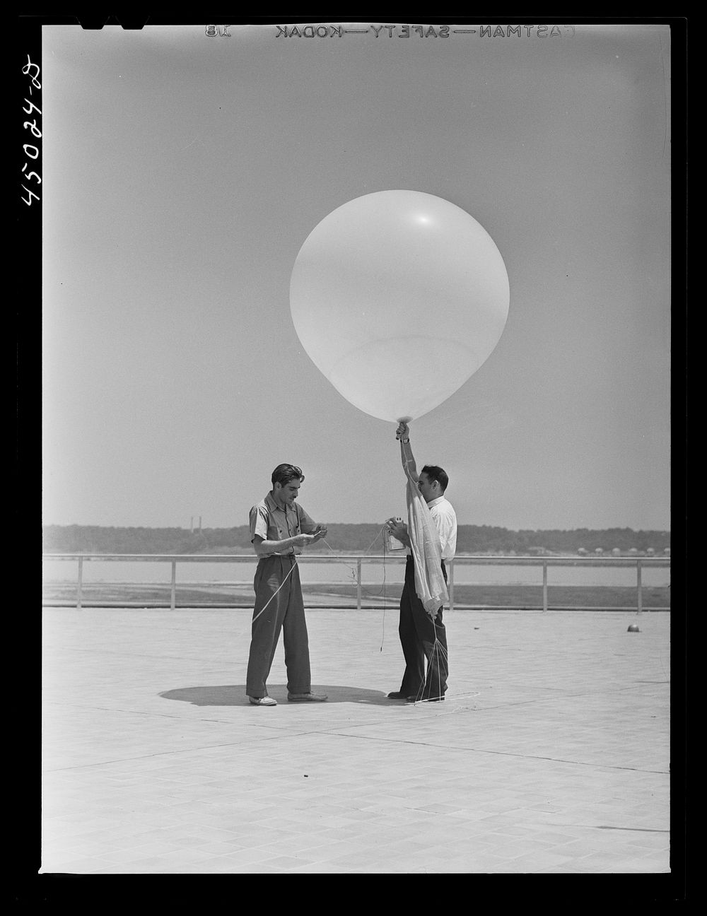 [Untitled photo, possibly related to: Weather Bureau men preparing to send up the balloon for weather data. Municipal…