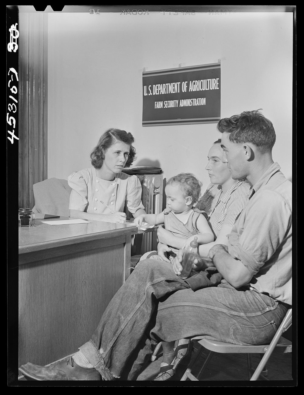 Mr. and Mrs. Carleton Allen and their daughter in the office of the New York Defense Relocation Corps discuss plans for…