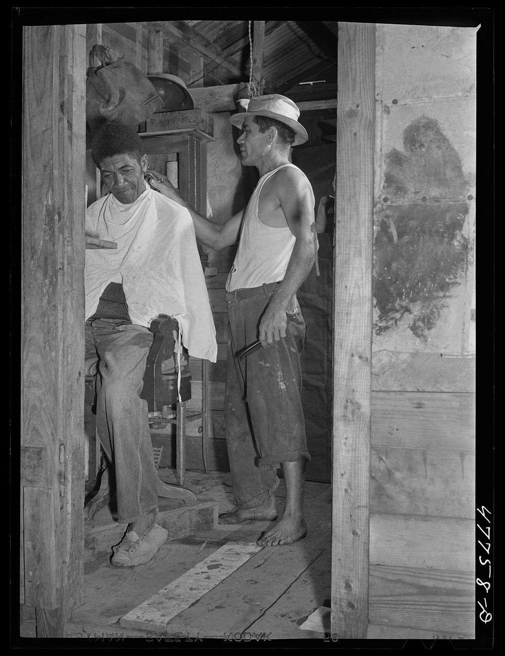 San Juan, Puerto Rico. A barber shop in the huge slum area known as "El Fangitto." The barber is a former radio mechanic and…