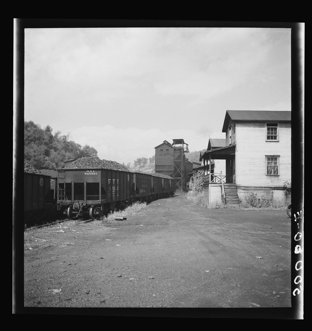 [Untitled photo, possibly related to: White coal miner going to work and  woman taking home groceries. Company houses, coal…