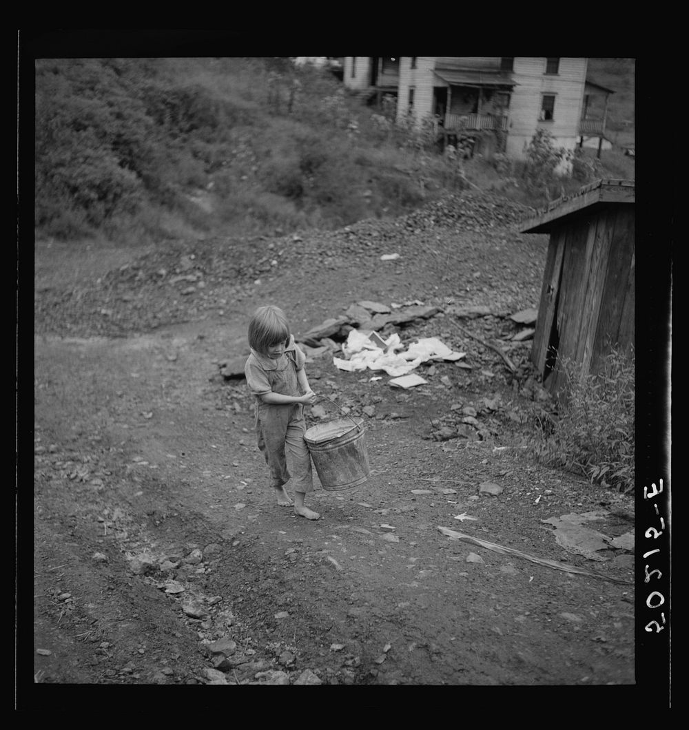 Child of miner carrying home coal she picked out of old slate pile down the hill. Pursglove, Scotts Run, West Virginia.…