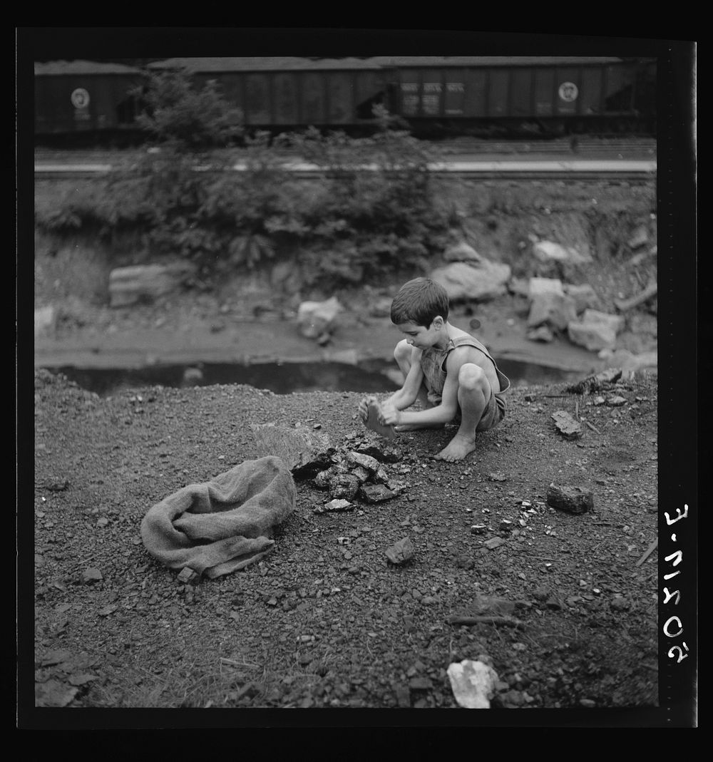 Coal miner's child breaking up large pieces of coal to take home. Pursglove, Scotts Run, West Virginia. Sourced from the…