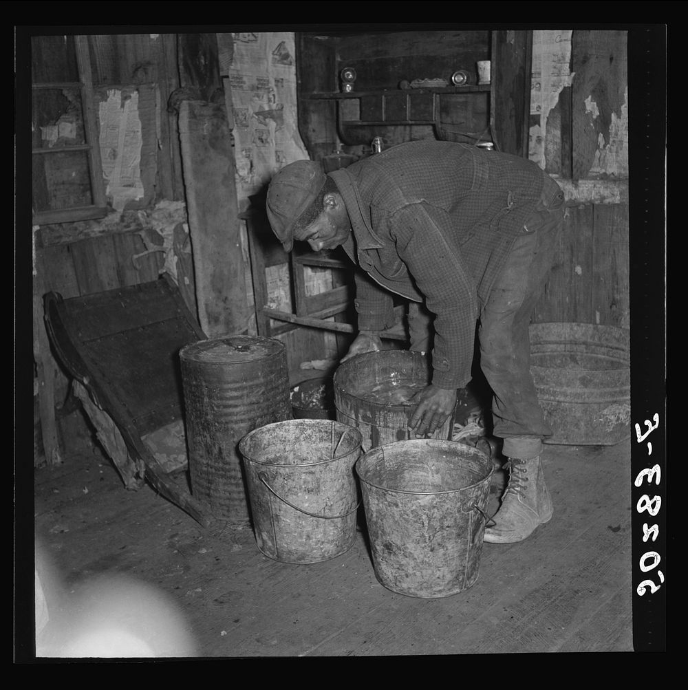 A neighbor (coal miner) taking away some slops for his pigs. Bertha Hill, West Virginia. Sourced from the Library of…
