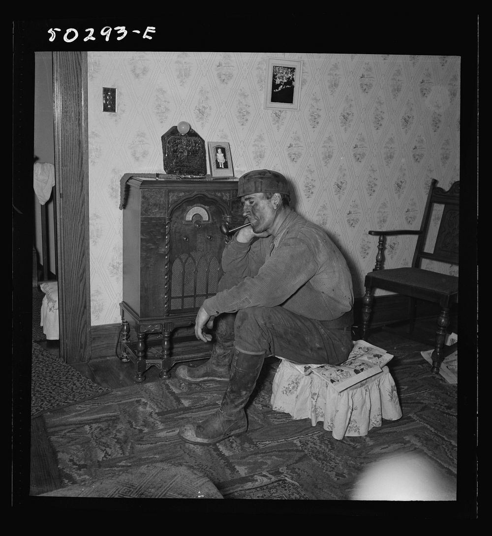 A more well-to-do miner listening to the radio when he returns home in the morning after working on the night shift. He is…