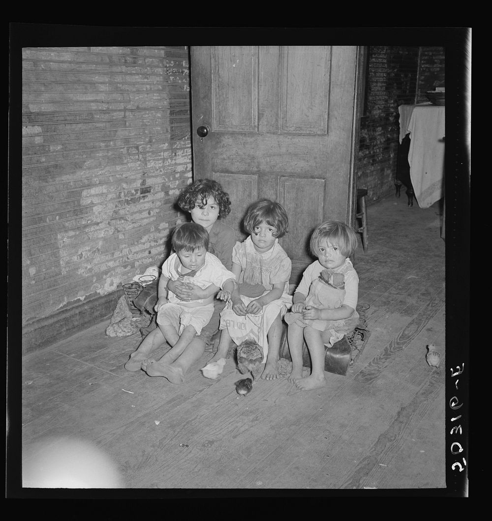 [Untitled photo, possibly related to: Mexican miner's children feeding chickens in the kitchen. Their mother is thirty years…