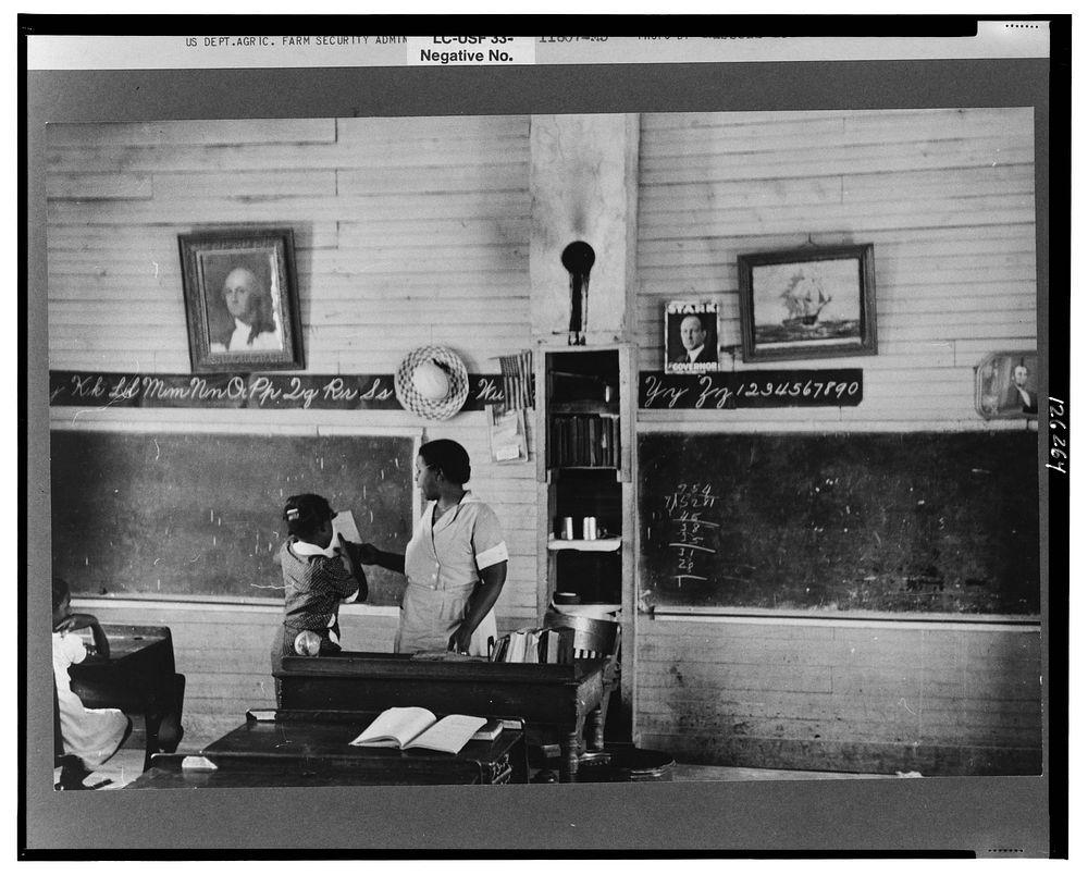 Schoolteacher explaining passage to pupil, La Forge, Missouri. School attended by Southeast Missouri Farms children by…