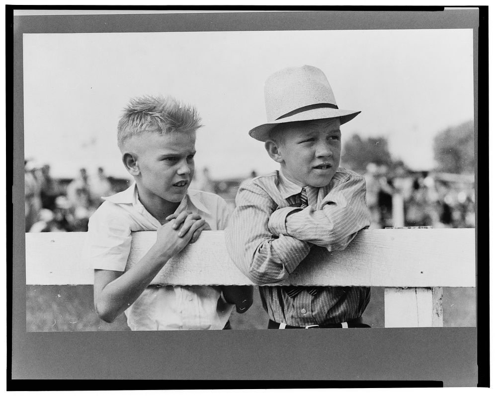 Two boys leaning on fence watching parade, state fair, Donaldsonville, Louisiana by Russell Lee