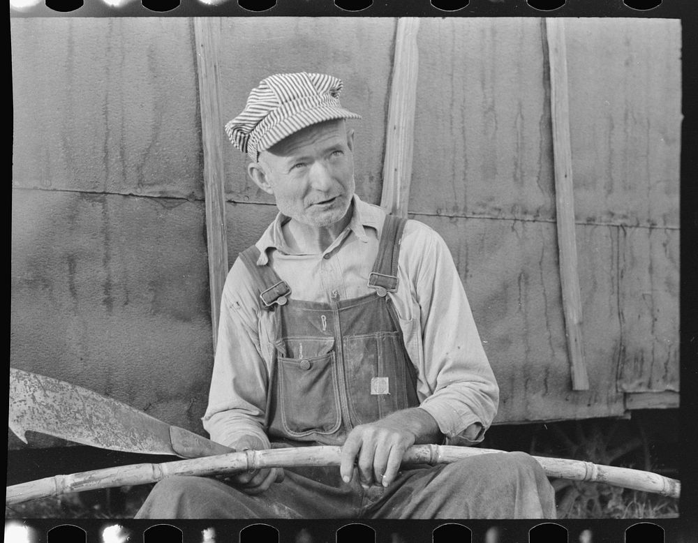 Day laborer with sugarcane knife in front of his shack home near New Iberia, Louisiana by Russell Lee