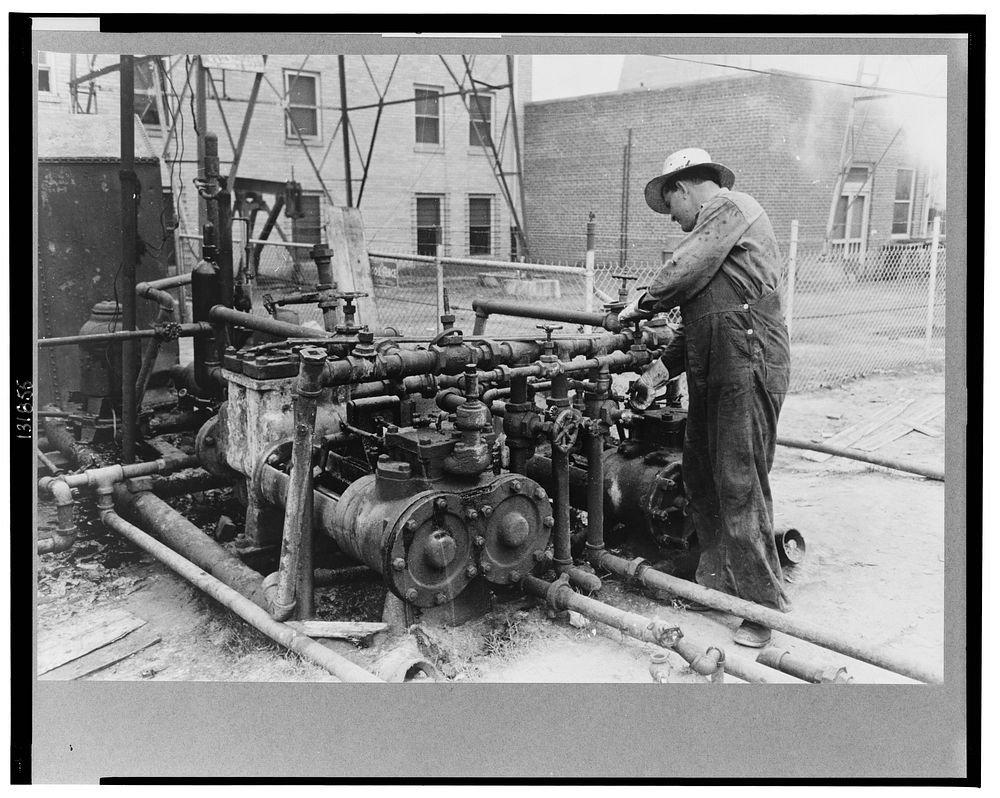 Oil field worker working on the mud hog, a machine which pumps the mud from the sluch pit through the drill pipe to the bit…