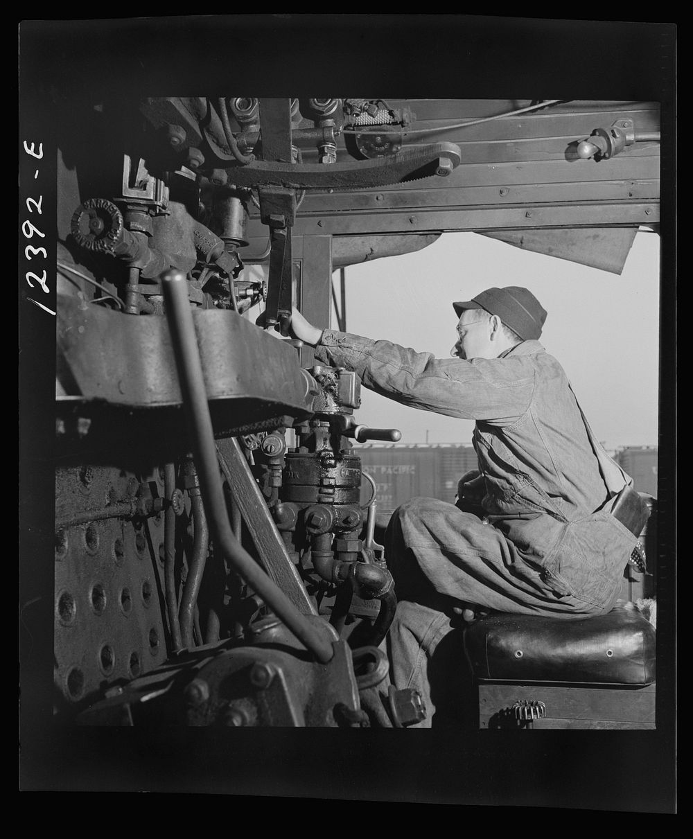 Chicago, Illinois. Engineer of an incoming locomotive in his cab at a Chicago and Northwestern Railroad yard. Sourced from…