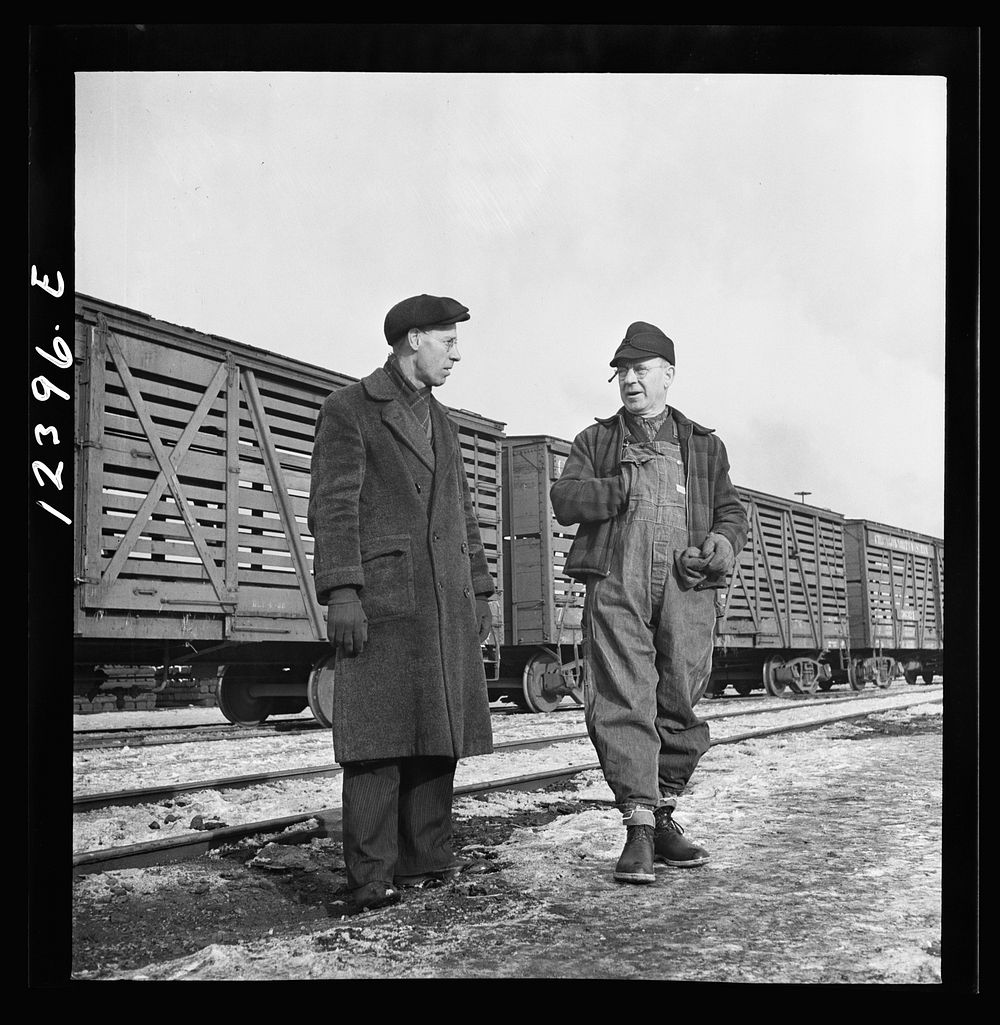 Chicago, Illinois. Freight conductor (right) talking to a yardmaster as he waits for the caboose of his train to come by at…