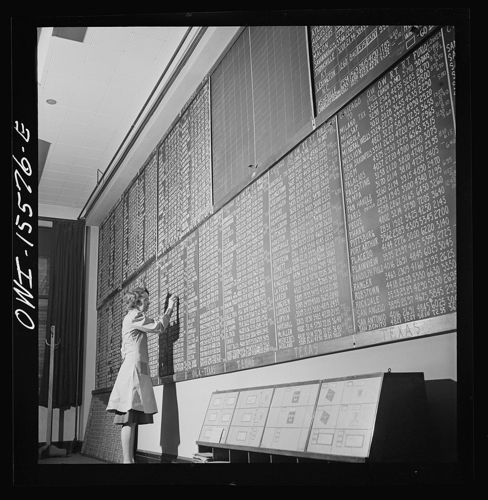 Chicago, Illinois. Mrs. Marie Griffith, manager of the information room, at one of the boards listing rates to points all…