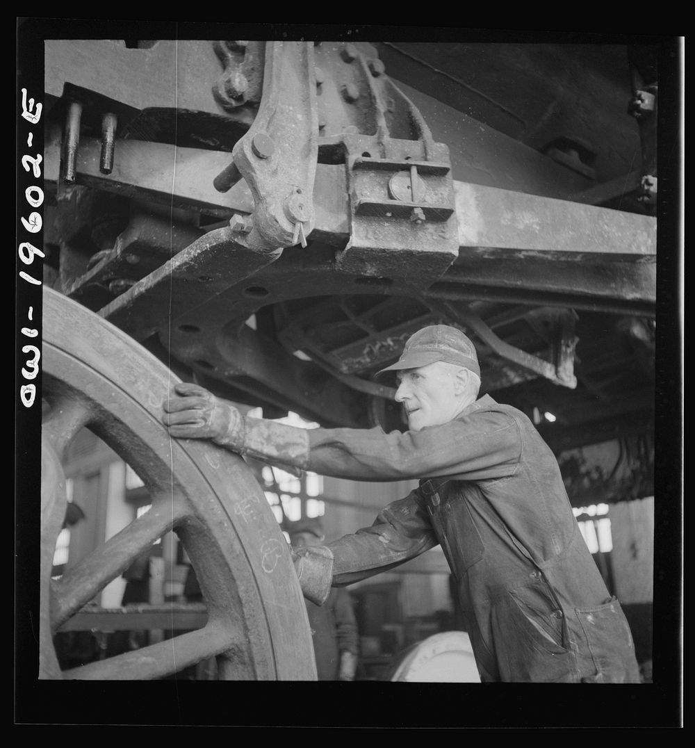 Fort Madison, Iowa. Edward E. Leonard pushing a driver wheel in place under an engine being wheeled at the Shopton…