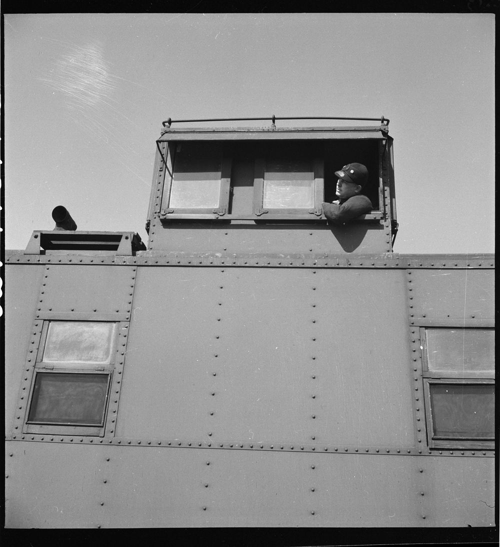 Marceline, Missouri. Brakeman in the cupola of his caboose in the Atchison, Topeka, and Santa Fe Railroad yard. Sourced from…