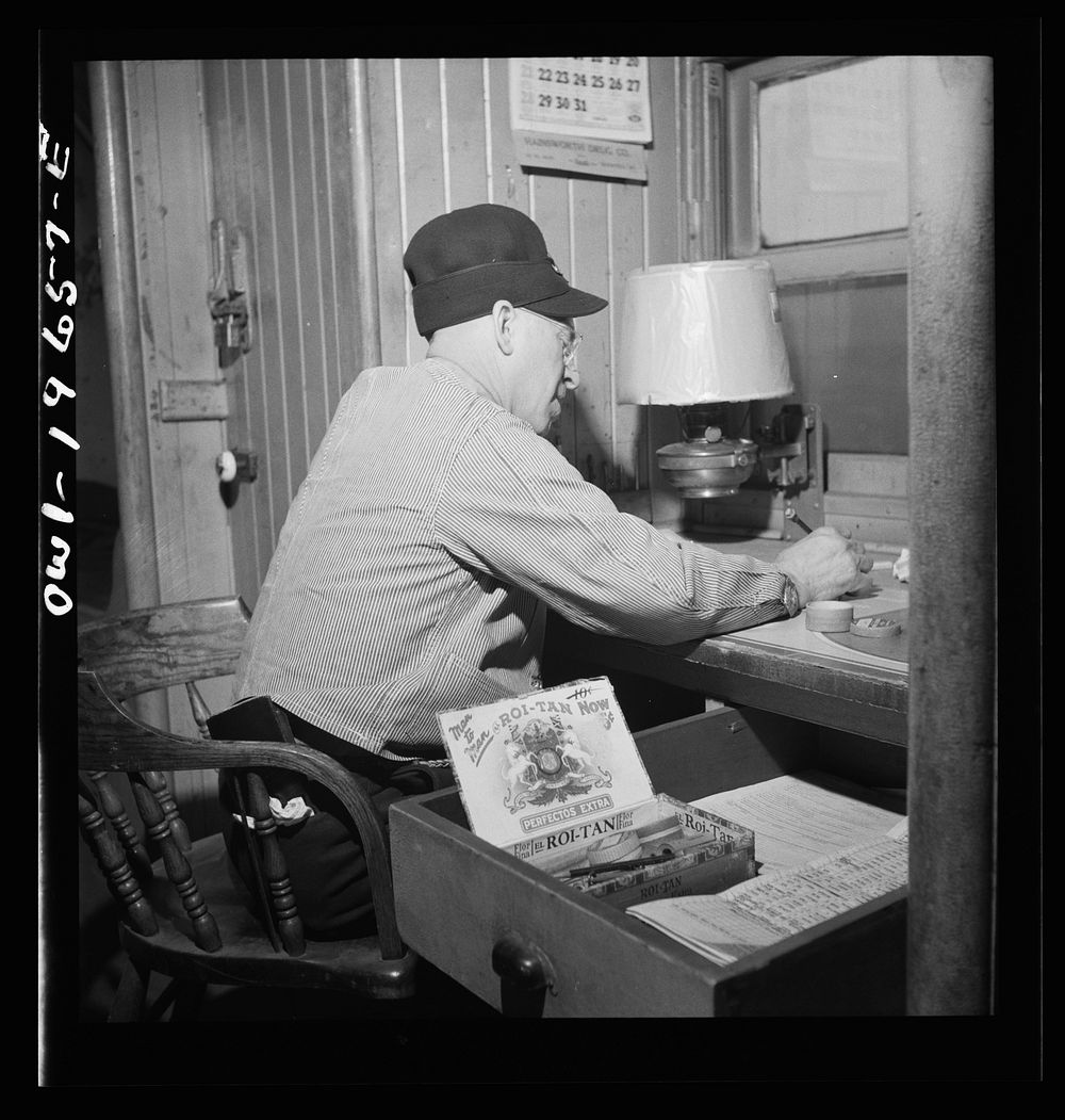 Conductor F. T. Granstaff, working on his records in the caboose on the Atchison, Topeka, and Santa Fe Railroad between…