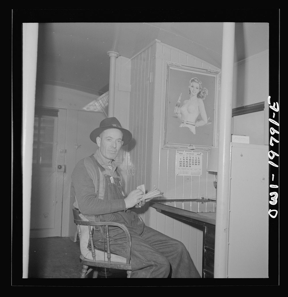 Conductor G. Reynolds, checking his waybills in the caboose of the Atchison, Topeka, and Santa Fe Railroad between Argentine…