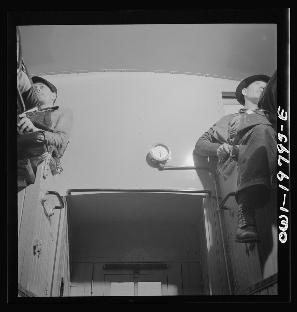 Conductor (right) and brakeman, in their places in the cupola of the caboose on the Atchison, Topeka, and Santa Fe Railroad…