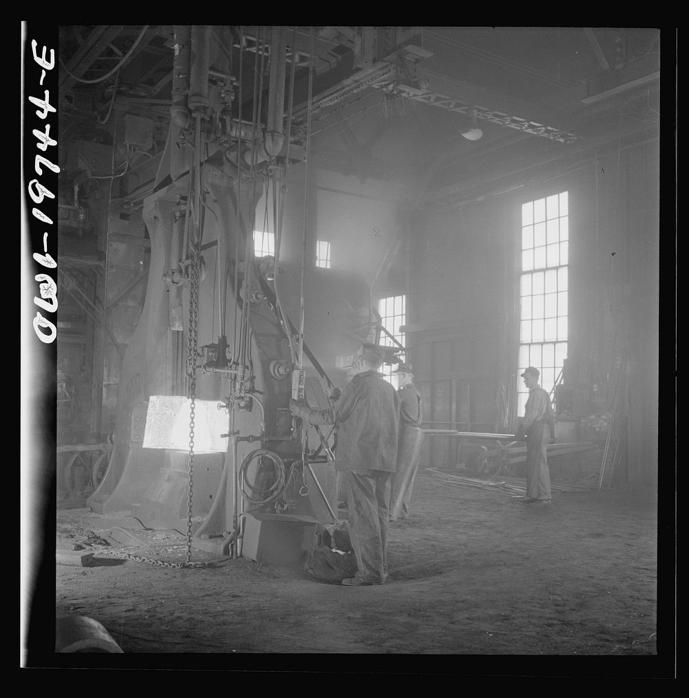 Topeka, Kansas. Hammering out a drawbar at the giant steam hammer in the smith shop of the Atchison, Topeka, and Santa Fe…