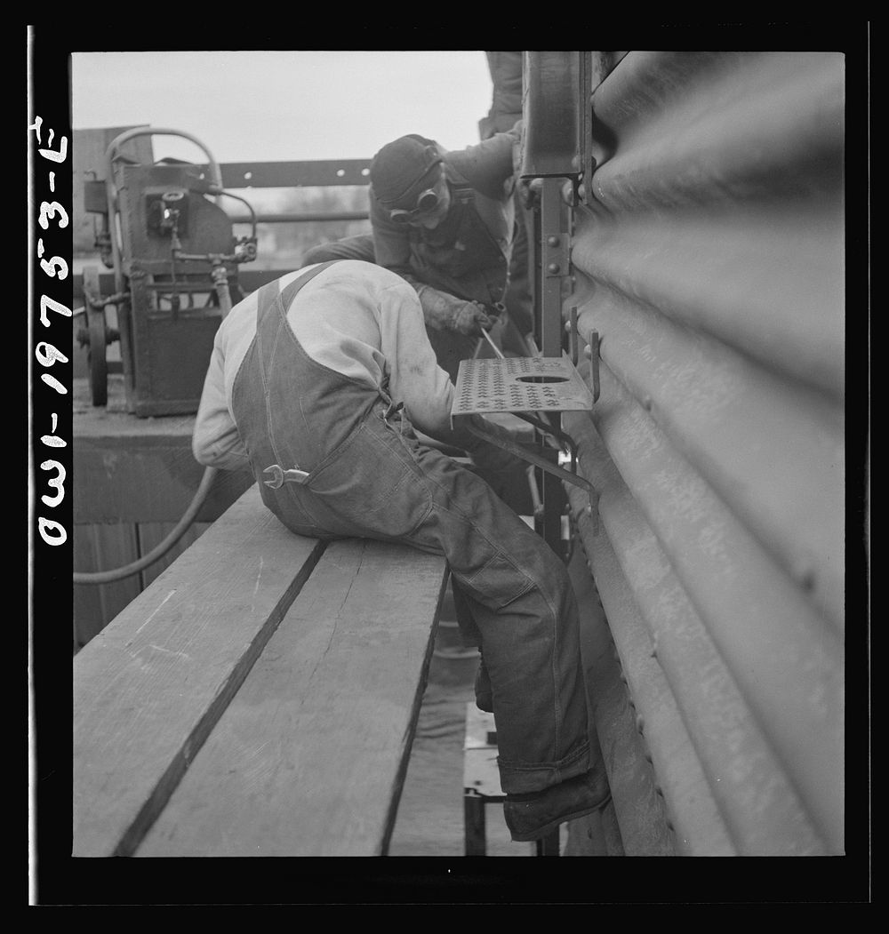 [Untitled photo, possibly related to: Topeka, Kansas. Bucking rivets on a freight car which is being rebuilt in the shops of…