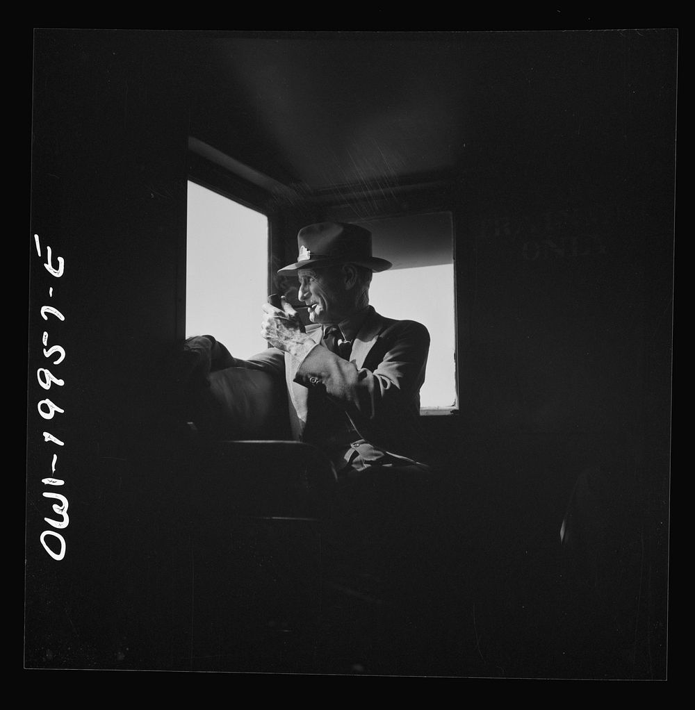 Conductor J.R. Crawford, watching the train from his window in the cupola of the caboose along the Atchison, Topeka, and…