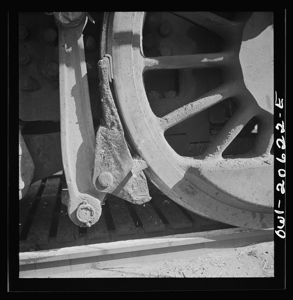 Clovis, New Mexico. Refacing the tires of a locomotive with a Ledgerwood apparatus. The locomotive is drawn down the rails…