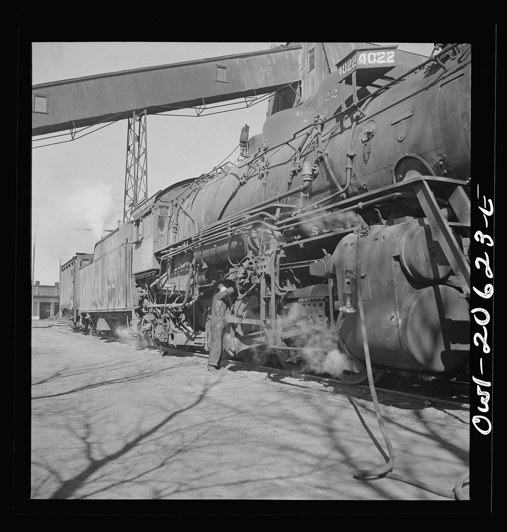 Clovis, New Mexico. Refacing the tires of a locomotive with a Ledgerwood apparatus. The locomotive is drawn down the rails…