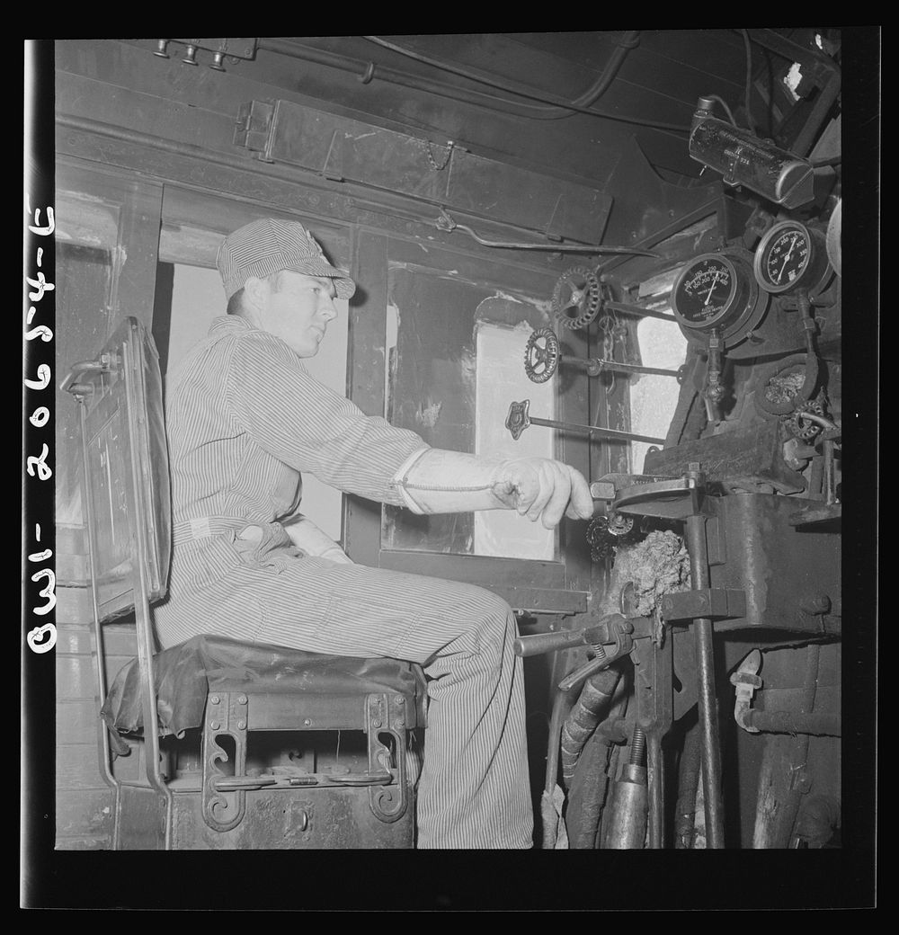 Ricardo, New Mexico. Fireman C.P. Fryer in his cab on the Atchison, Topeka, and Santa Fe Railroad, between Clovis and…