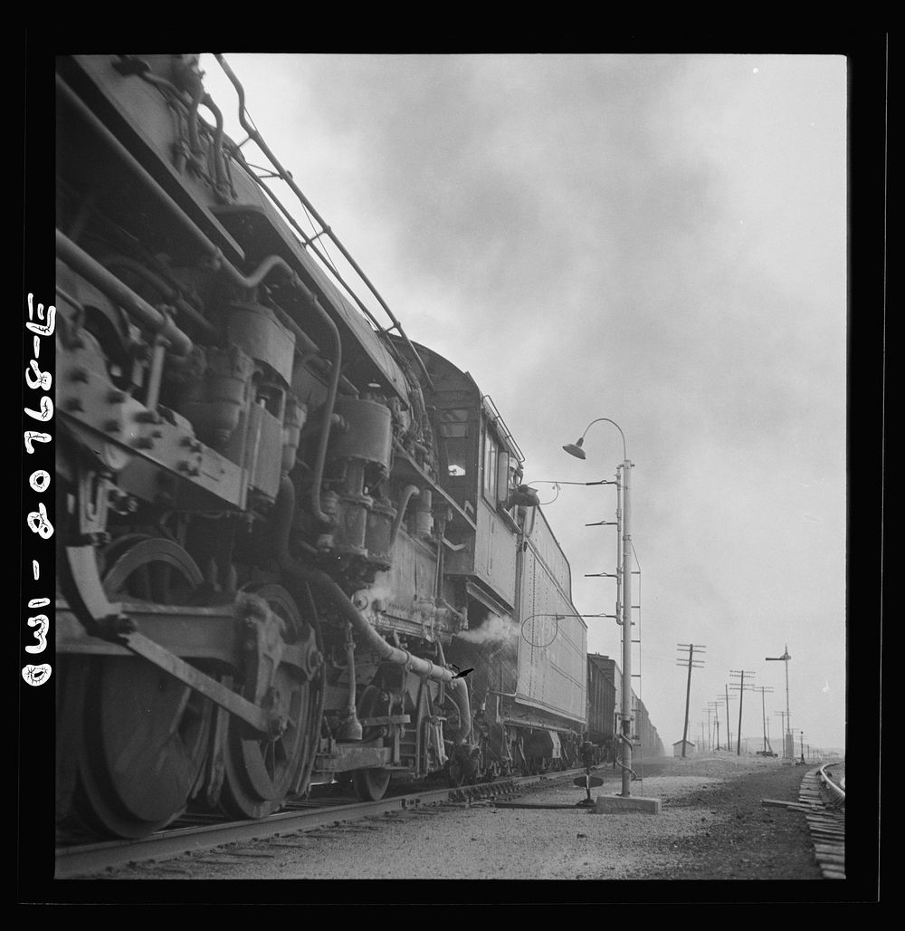 Isleta, New Mexico. Fireman of a passing freight train on the Atchison, Topeka and Santa Fe Railroad picking up a message.…