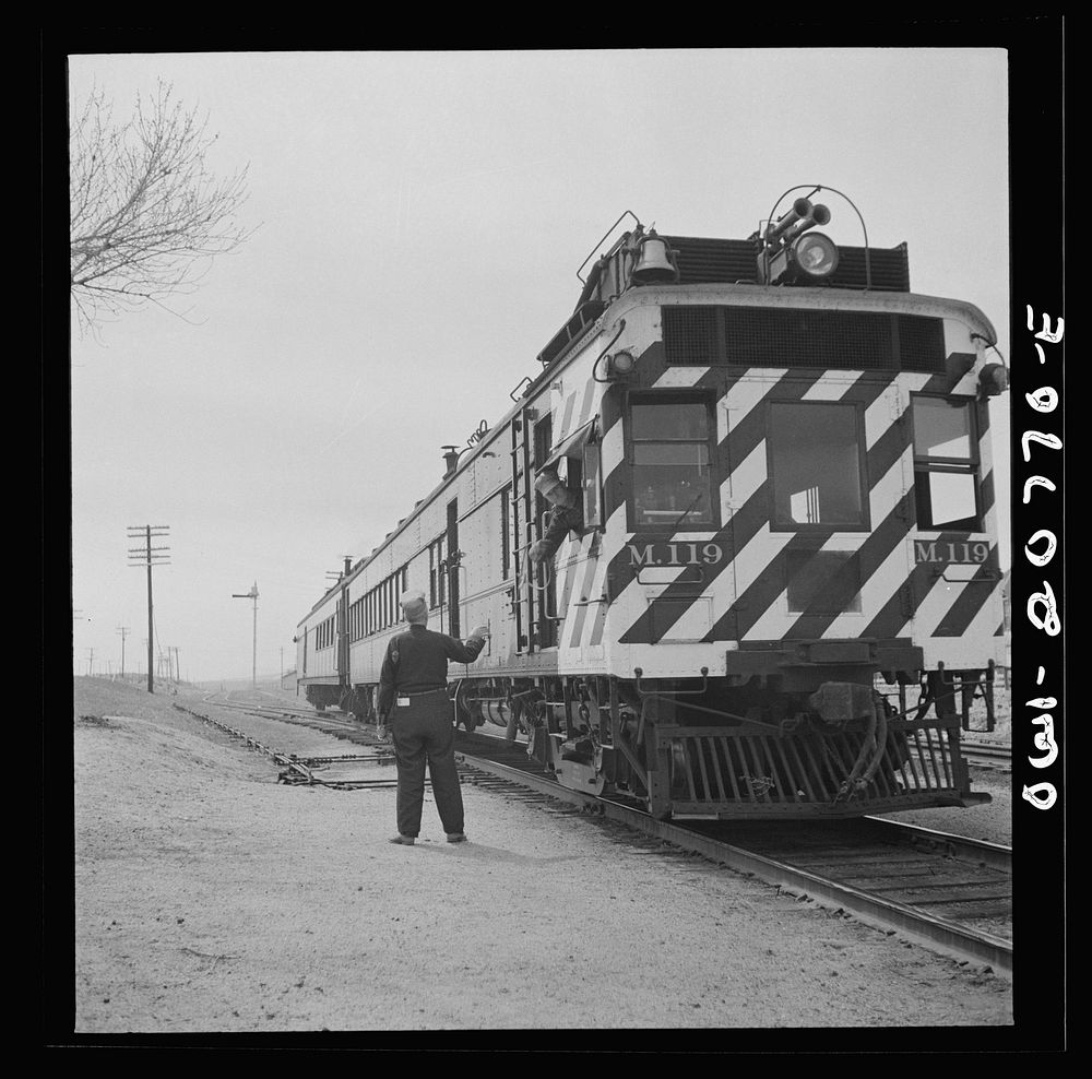 Isleta, New Mexico. Engineer of a passenger train on the Atchison, Topeka and Santa Fe Railroad picking up a message passed…