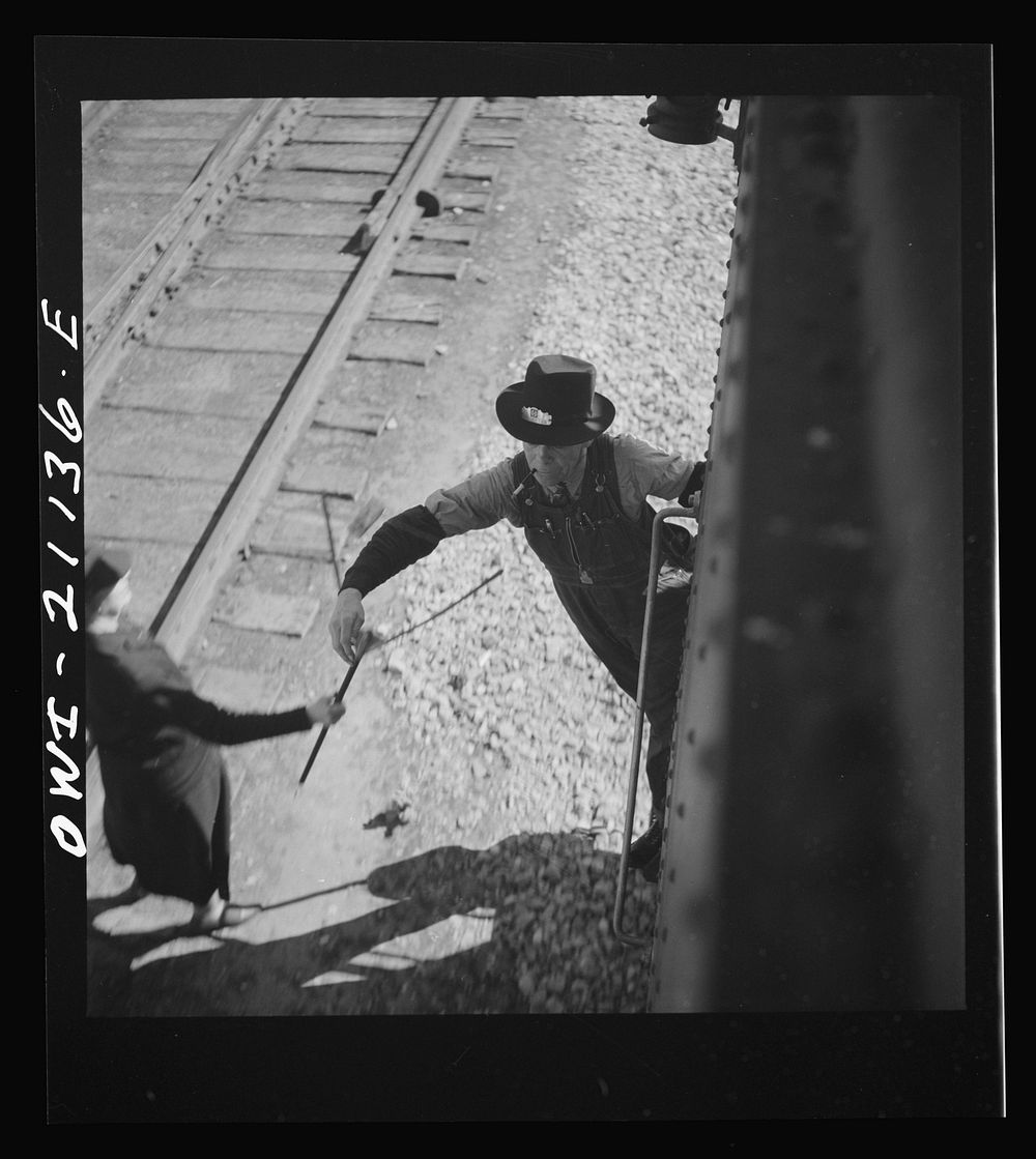 Dalies, New Mexico. Conductor C.W. Tevis picking up a message from a woman operator on the Atchison, Topeka and Santa Fe…