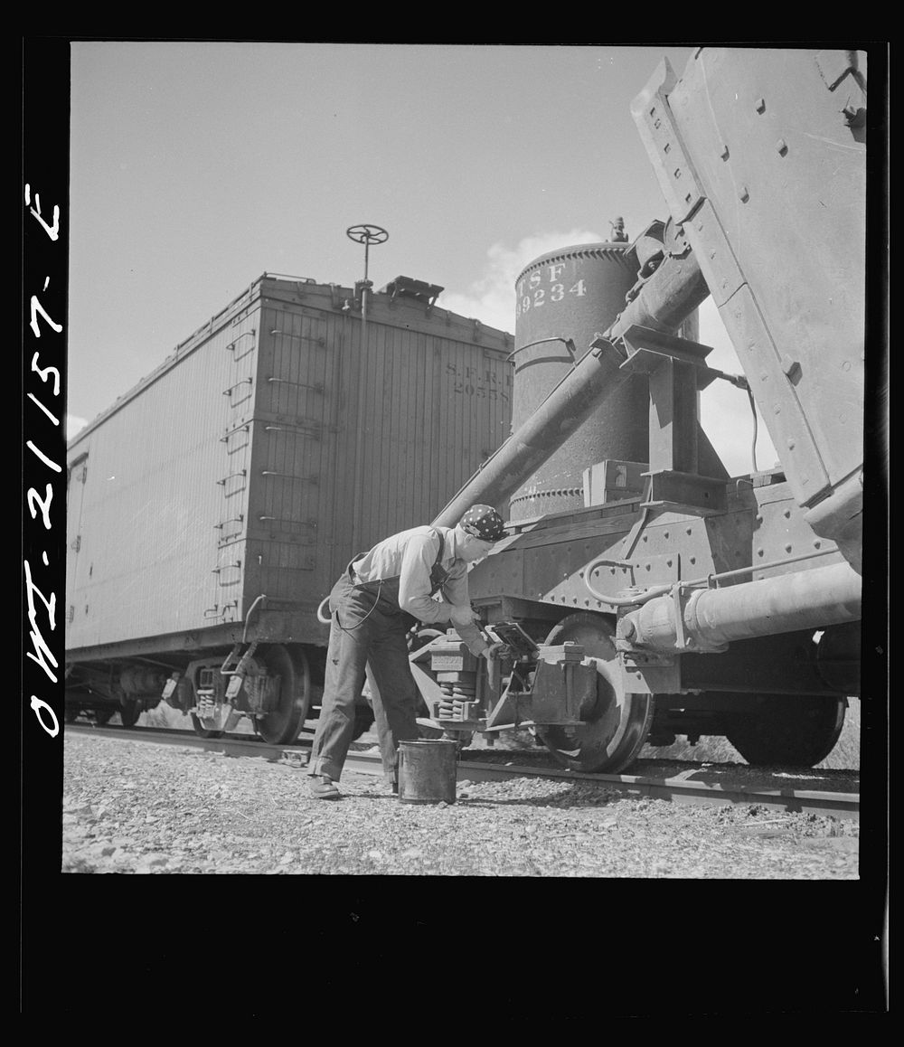Acomita, New Mexico. Brakeman R.E. Capsey repacking a journal box of a special car as the train on the Atchison, Topeka and…