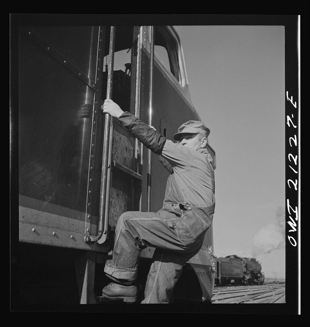 Winslow, Arizona. Engineer George Bertino climbing into the cab of a diesel freight engine in the Atchison, Topeka and Santa…