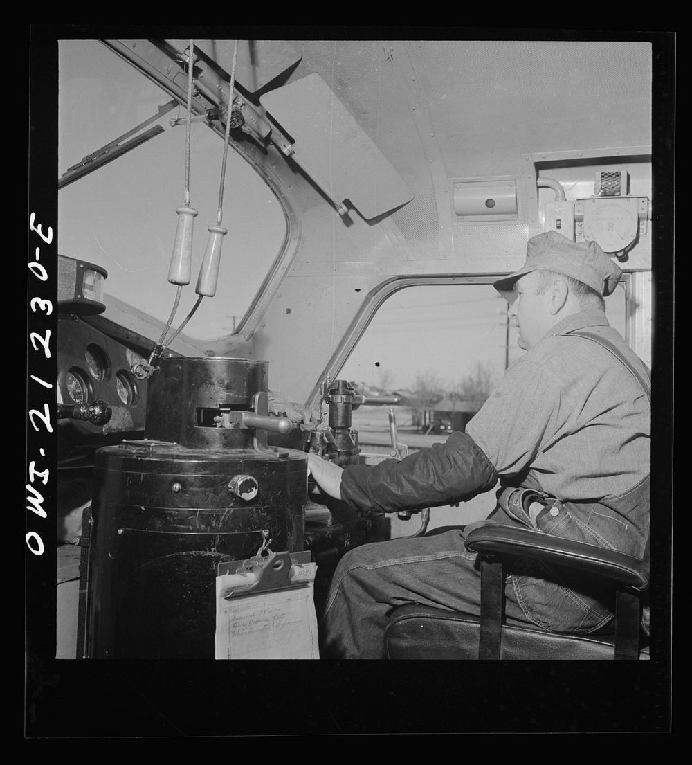 Winslow, Arizona. Engineer George Bertino in the cab of his diesel freight engine, ready to pull out of the Atchison, Topeka…