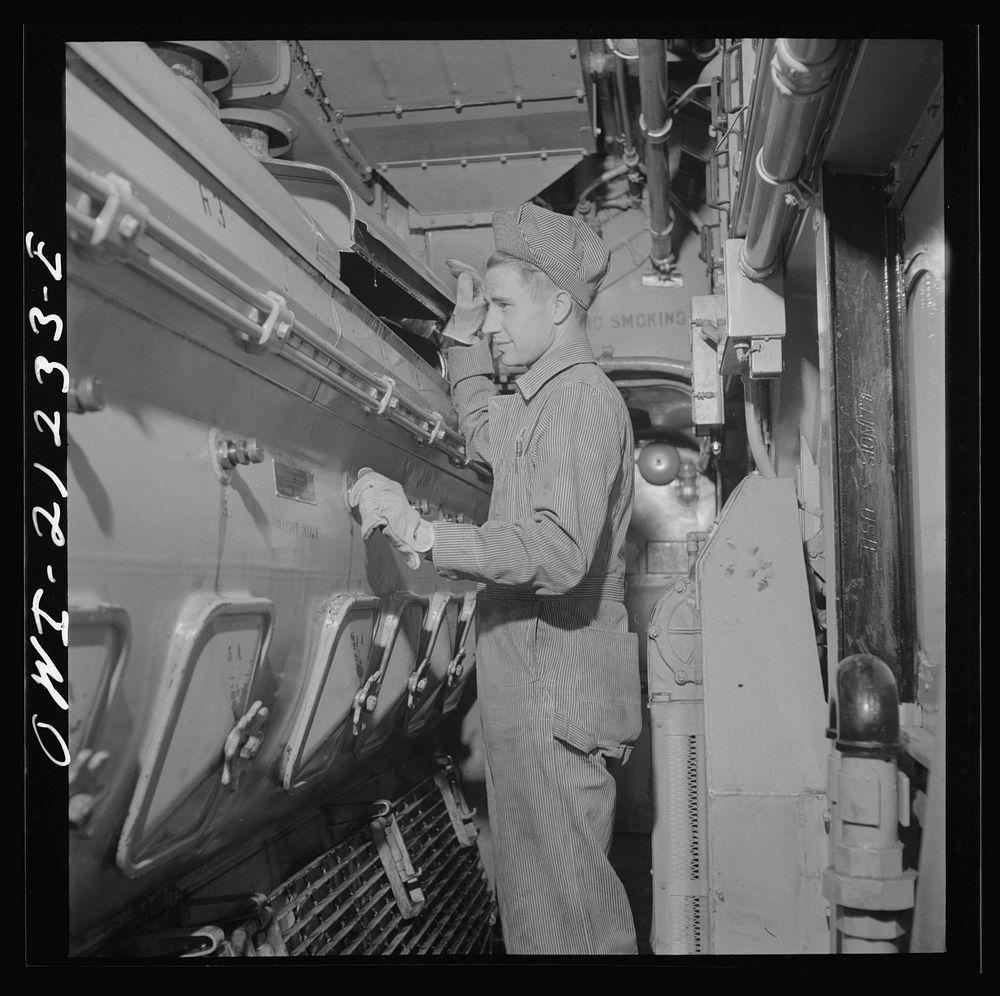 Winslow, Arizona. W.F. Leverenz, maintainer, at work on one of the units of the diesel freight locomotive in the Atchison…