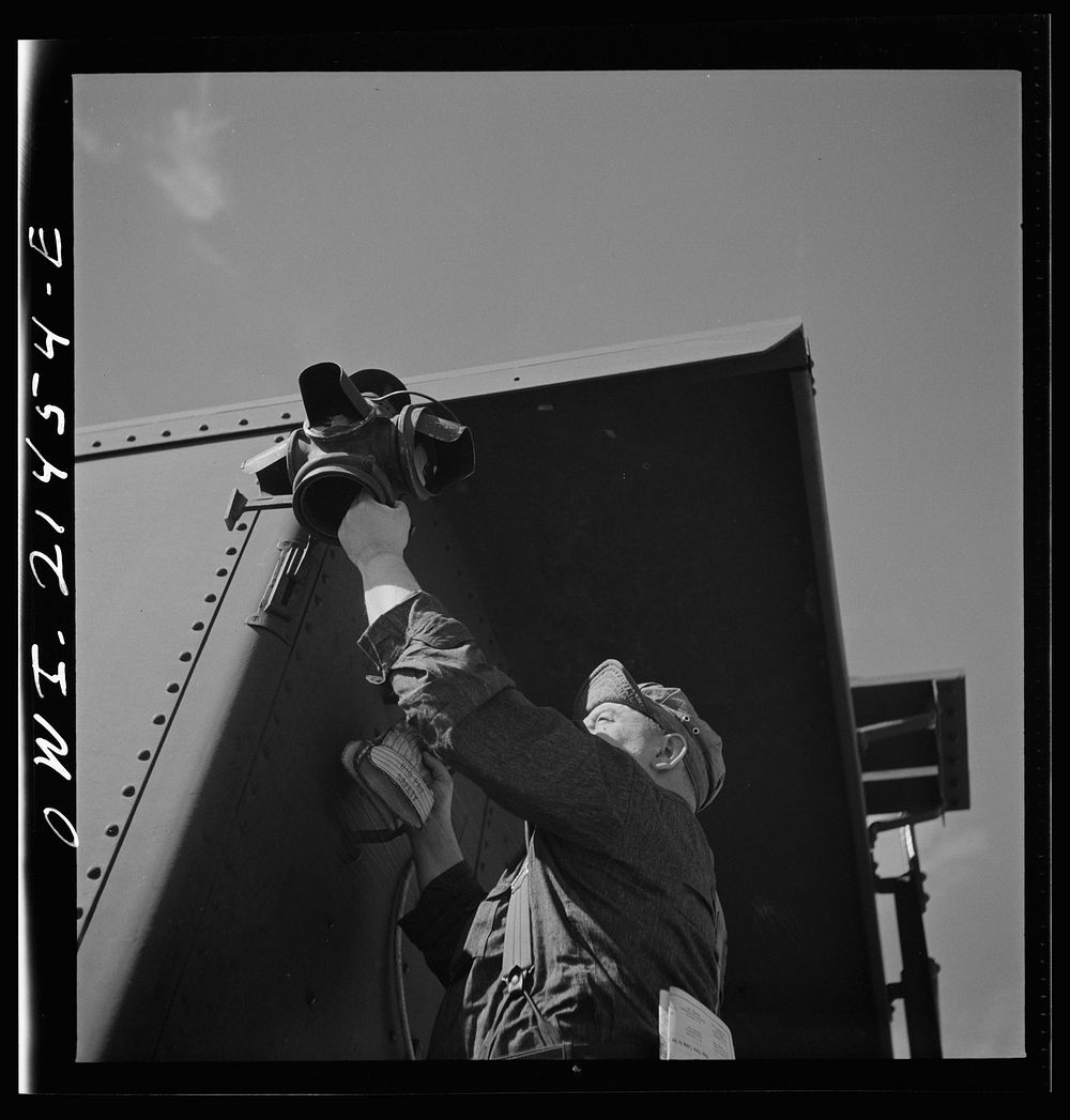 Ludlow, California. Brakeman hanging up a hooded marker as the Atchison, Topeka and Santa Fe train approaches. Sourced from…