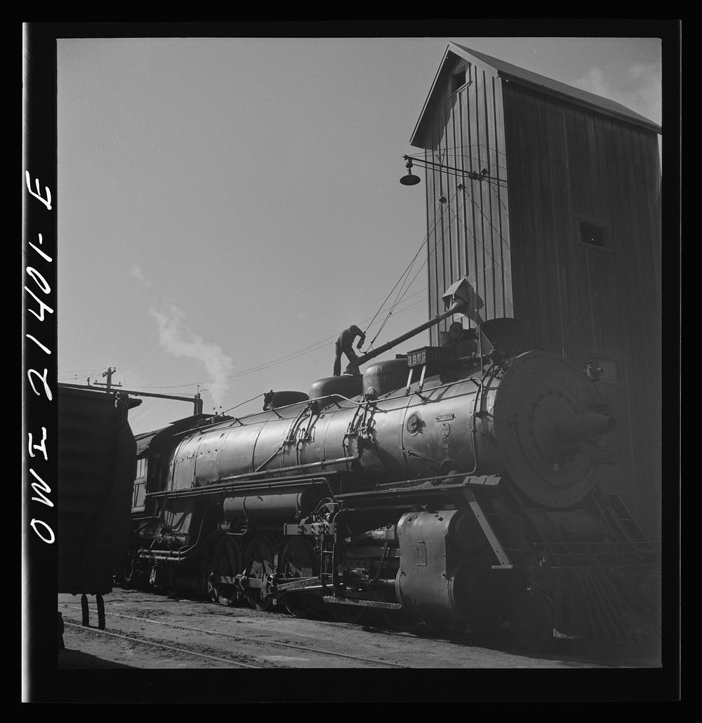 Needles, California. Filling the sand dome of a locomotive near the roundhouse in the Atchison, Topeka, and Santa Fe…