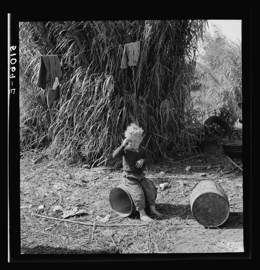 Child of packinghouse workers from Tennessee, his face covered with  muck which causes an itchy rash.  Belle Glade, Florida.…
