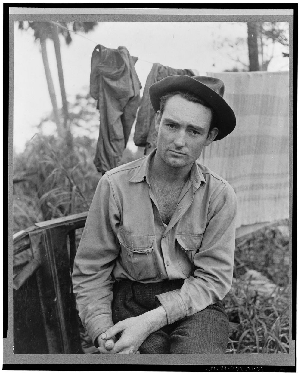 A migrant laborer waiting for work in one of the packing houses near Canal Point, Florida. Sourced from the Library of…