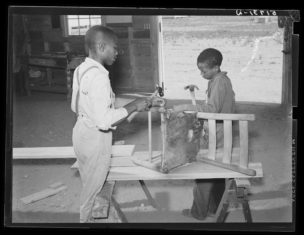 John Young and J.W. West repairing a chair in school shop class. Flint River Farms, Georgia. Sourced from the Library of…