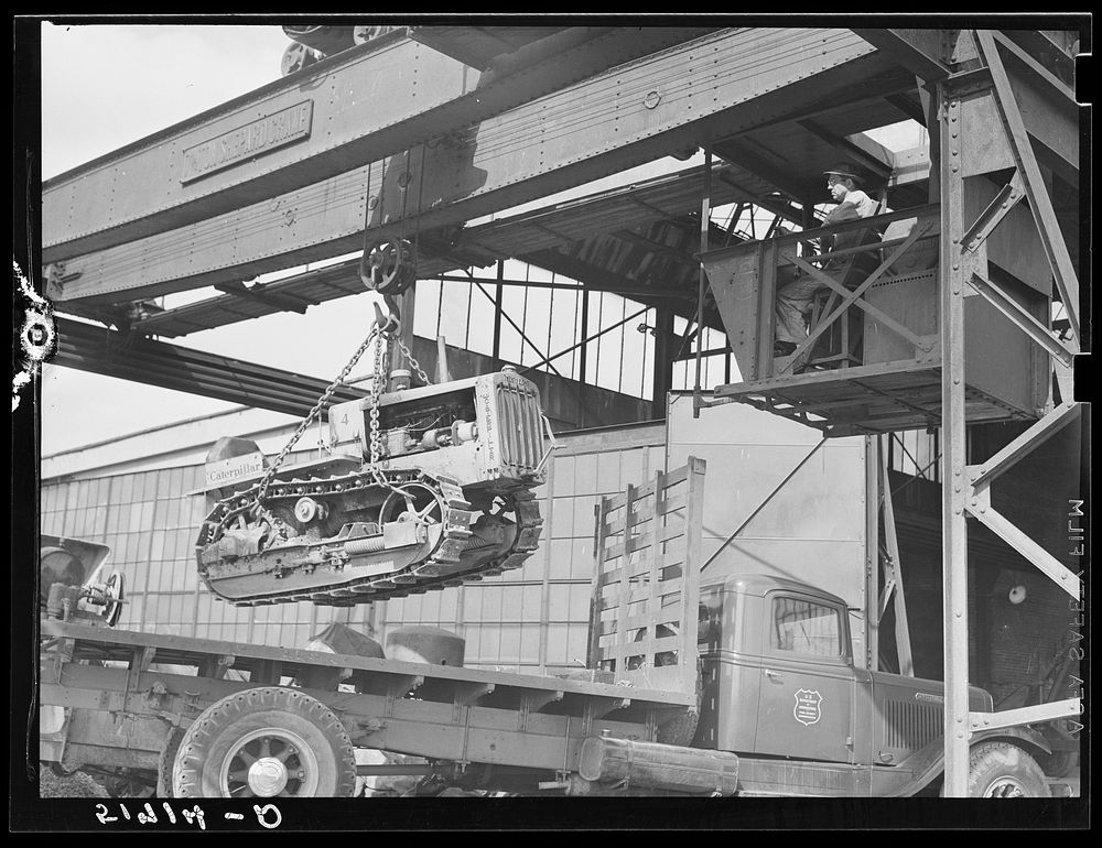 Tractor, transported by truck to FSA (Farm Security Administration) warehouse depot for repairs, being hoisted by Shepard…