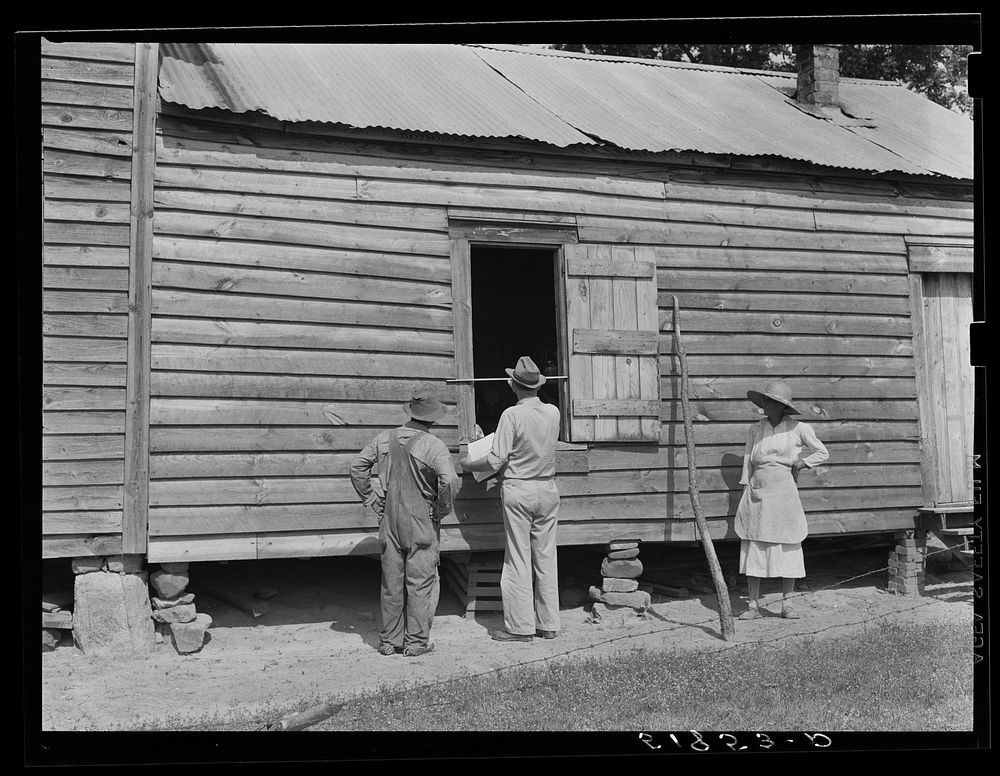 FSA (Farm Security Administration) supervisor measuring windows of Henry Mitchell's home for screens. Greene County…