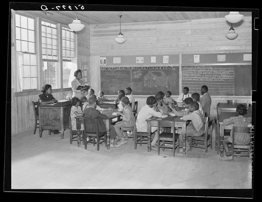 Classroom showing varying ages of students in primary grades in school. Prairie Farms, Alabama. Sourced from the Library of…