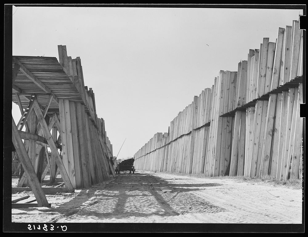 [Untitled photo, possibly related to: Stacks of lumber with tractor in planing mill. Cairo, Georgia]. Sourced from the…