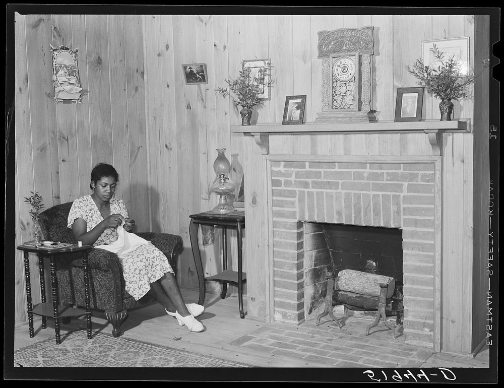 Daughter of Frederick Oliver, tenant purchase client, sewing in living room of new home. Summerton, South Carolina. Sourced…