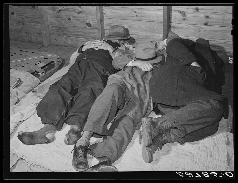 Farmers sleeping in white camp room in warehouse. They often must remain overnight or several days before their tobacco is…