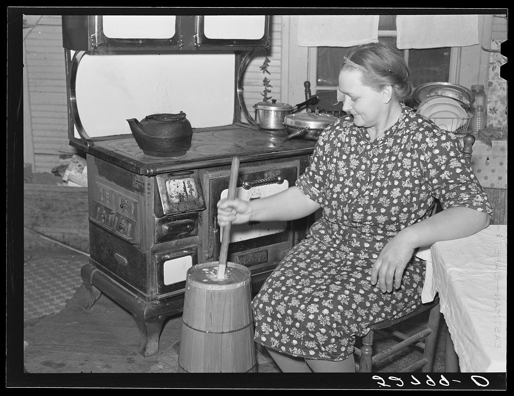 Mrs. Elvin Wilkins (Rosa) churning butter in the kitchen of their home in Tallyho. Near Stem, Granville County, North…