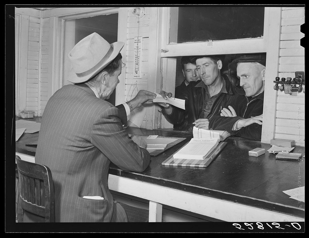 Farmers getting their checks in warehouse office after their tobacco has been sold at auction. Durham, North Carolina.…