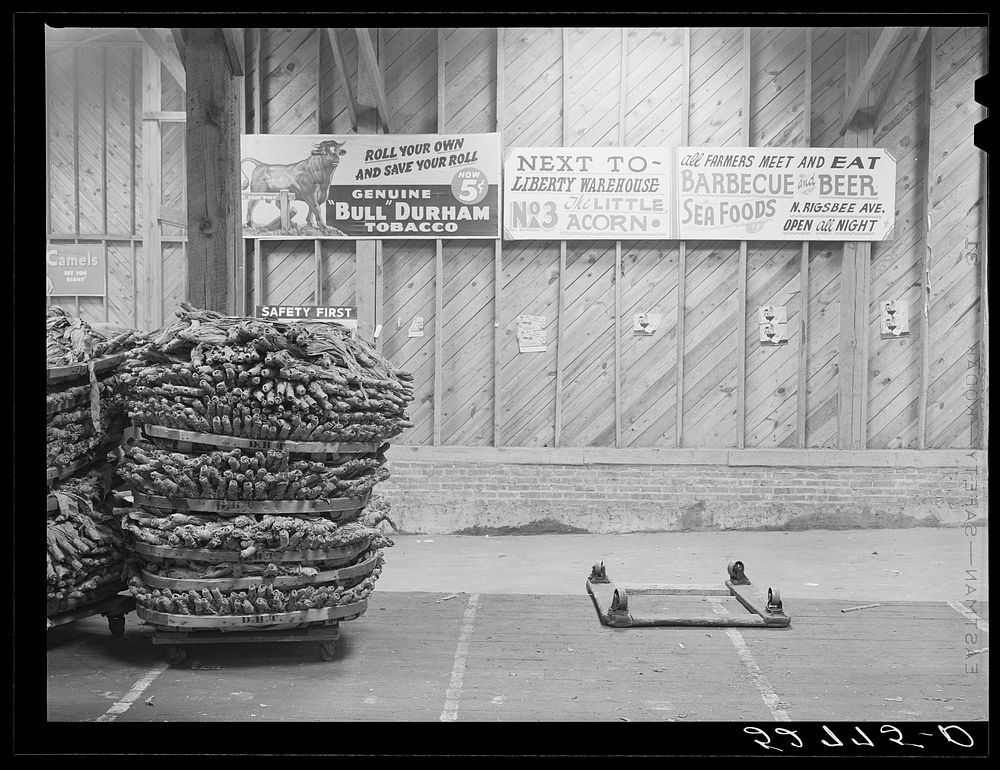 Baskets of tobacco piled on top of each other after being sold at auction. Here they are picked up by the trucks which haul…