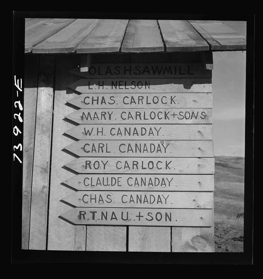 [Untitled photo, possibly related to: Ola, Idaho. A sign on the road points to a sawmill and farms of members of the Ola…